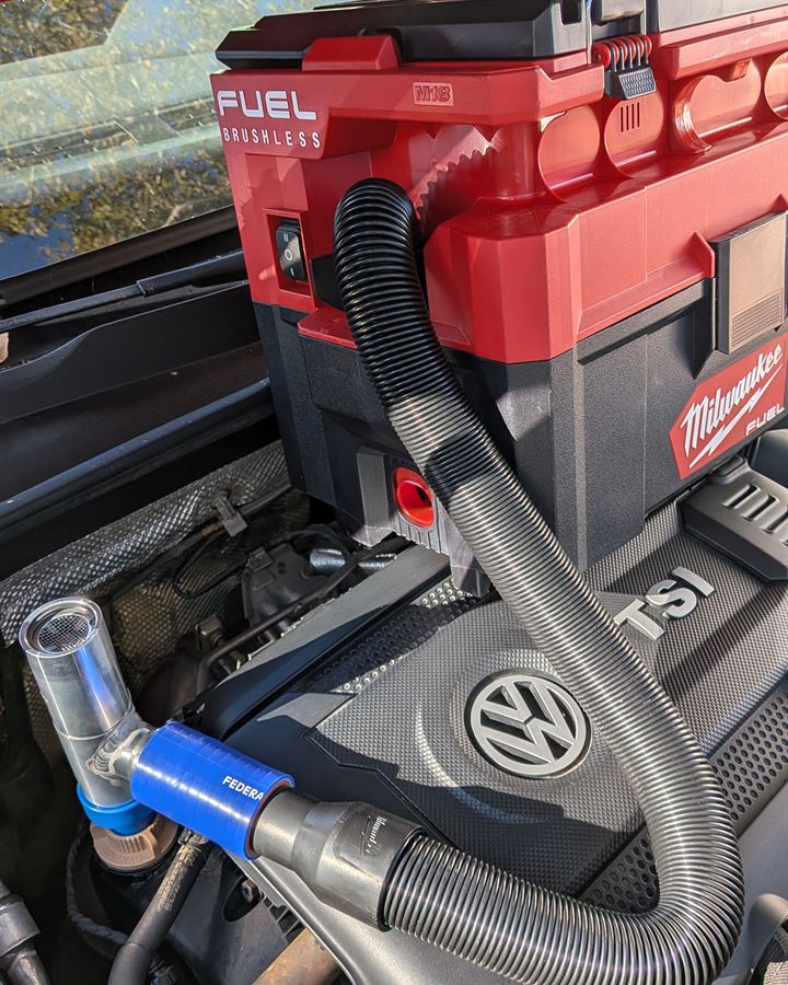 Vacuum hose connected to a car's engine during an oil change.