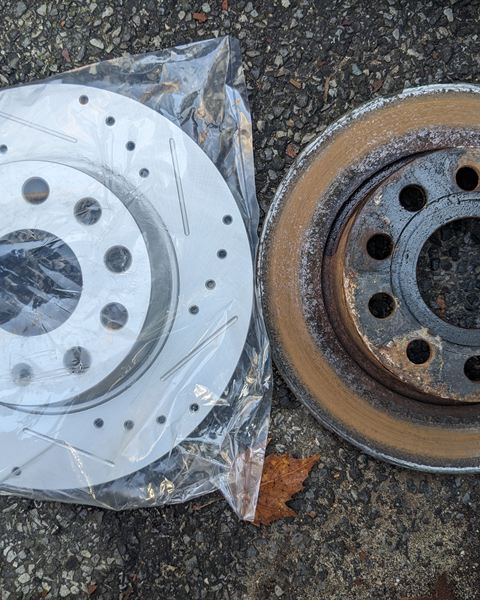 New drilled and slotted brake rotor next to the worn rotor it replaced.