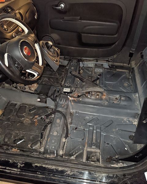 Car interior stripped down to the metal floor during a flood restoration.