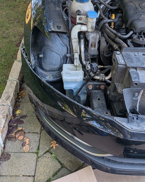 Front bumper and headlight removed from a black car.