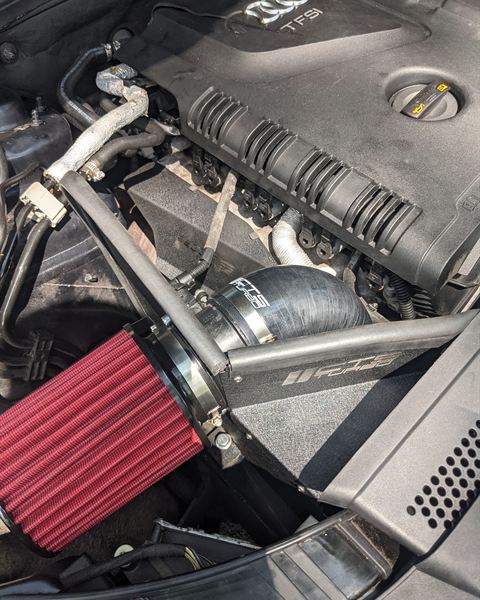Aftermarket cold air intake with a red filter installed in an Audi engine bay.