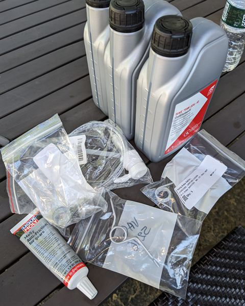 Bottles of transmission fluid, sealant and new parts laid out for the job.