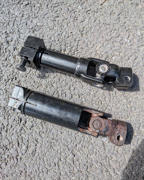 Two steering shafts laid out on the pavement.