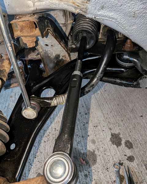 Front suspension with the control arm and axle exposed during a repair.
