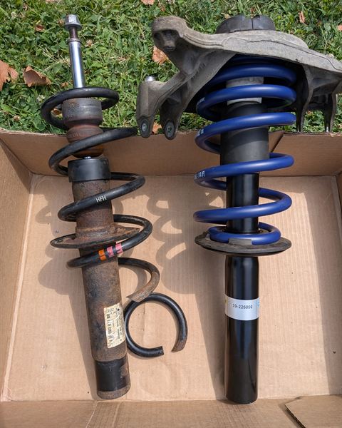 Old strut next to a new coilover with a blue spring, in a box.